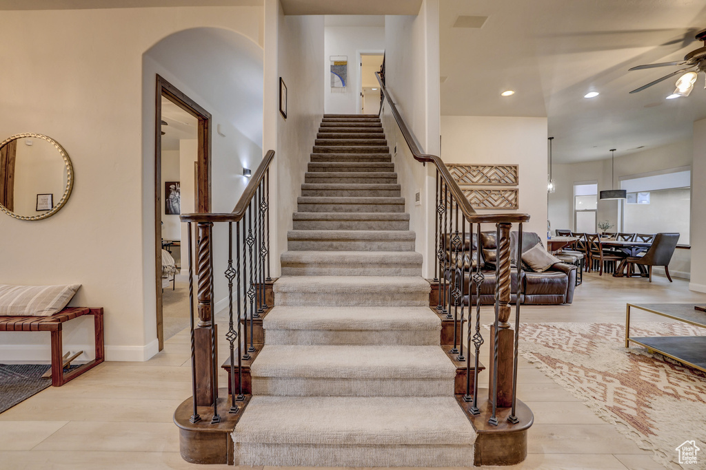 Staircase featuring ceiling fan, wood finished floors, recessed lighting, and arched walkways