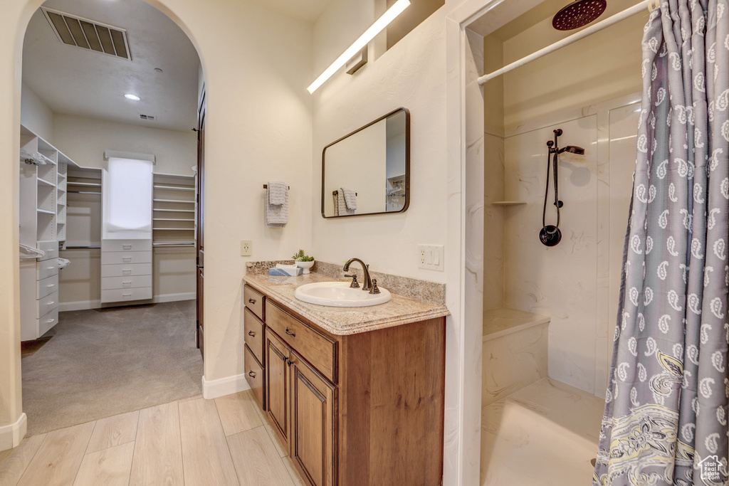 Bathroom with vanity, a walk in closet, curtained shower, and wood finished floors