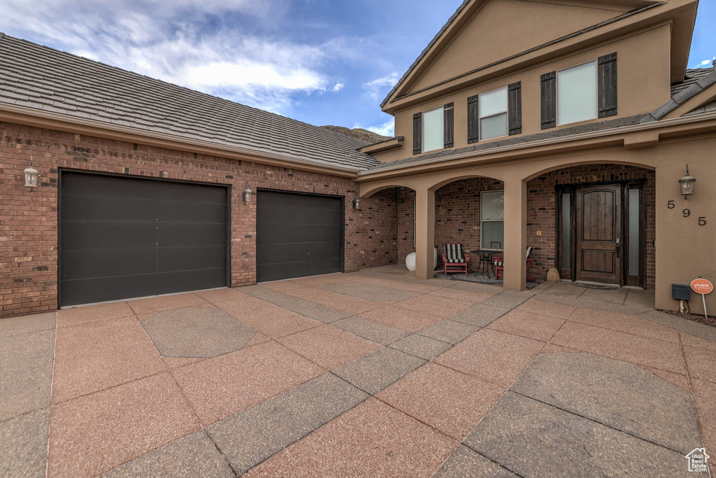 View of front of property featuring brick siding, driveway, covered porch, and stucco siding
