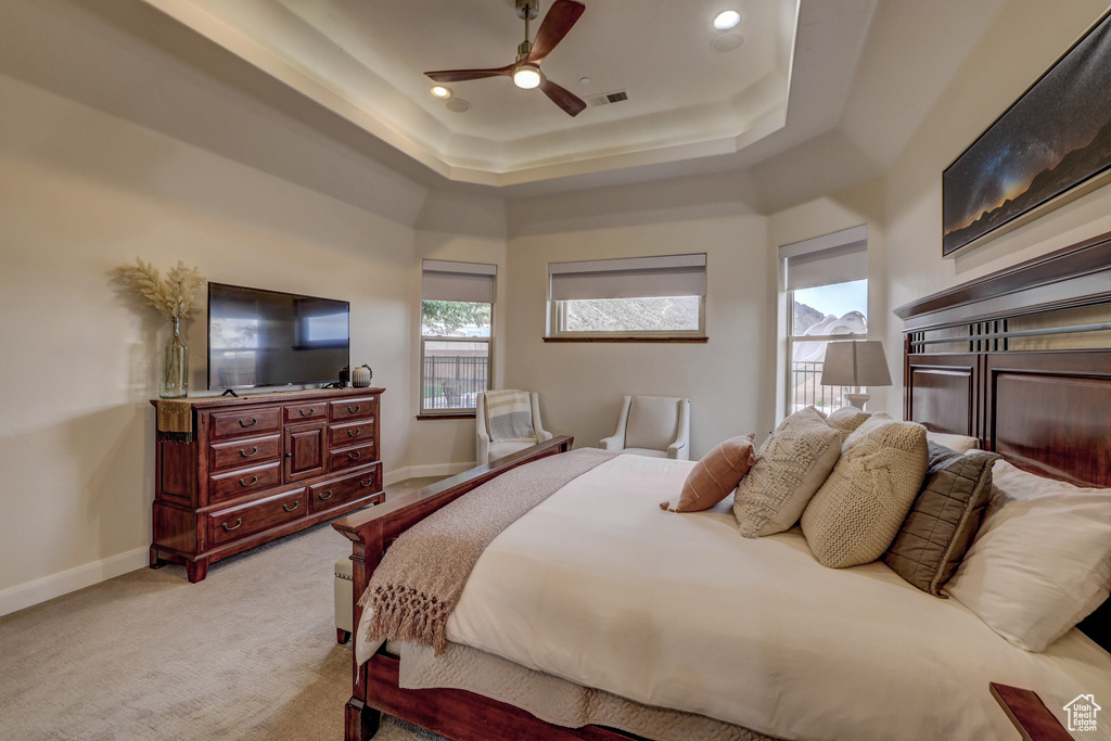 Bedroom with light carpet, a tray ceiling, a ceiling fan, and recessed lighting