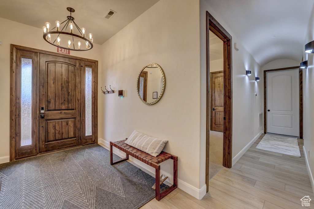 Foyer featuring lofted ceiling, a chandelier, and light wood-style floors