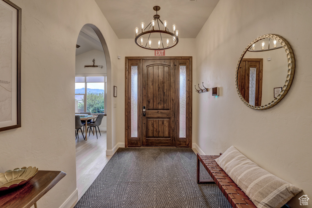 Foyer entrance featuring a chandelier, arched walkways, and lofted ceiling