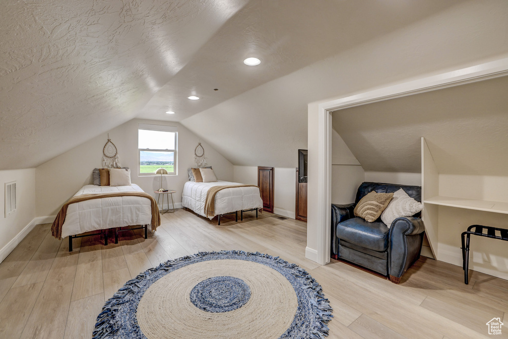 Bedroom with light wood finished floors, lofted ceiling, and recessed lighting