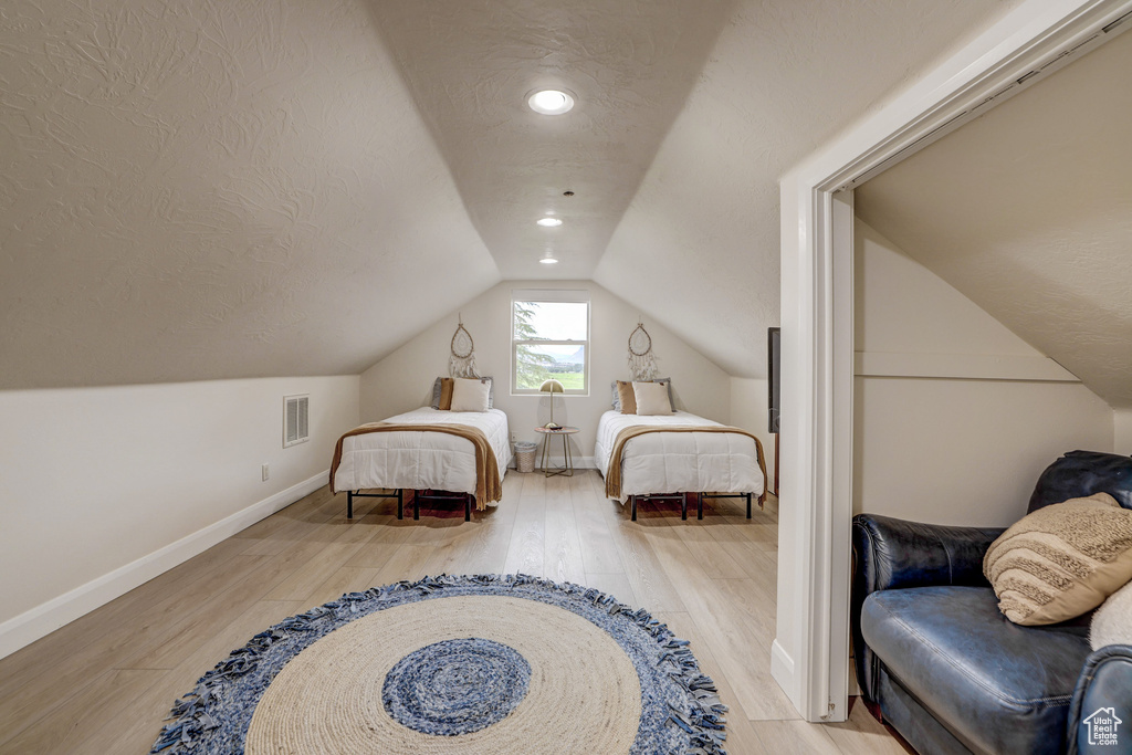 Bedroom with wood finished floors, vaulted ceiling, a textured ceiling, and recessed lighting