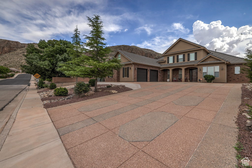 View of front facade featuring an attached garage, driveway, stucco siding, and a mountain view
