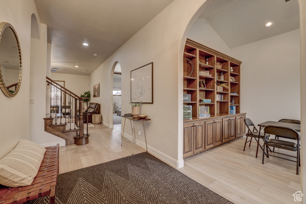 Entryway with light wood finished floors, arched walkways, recessed lighting, and stairway