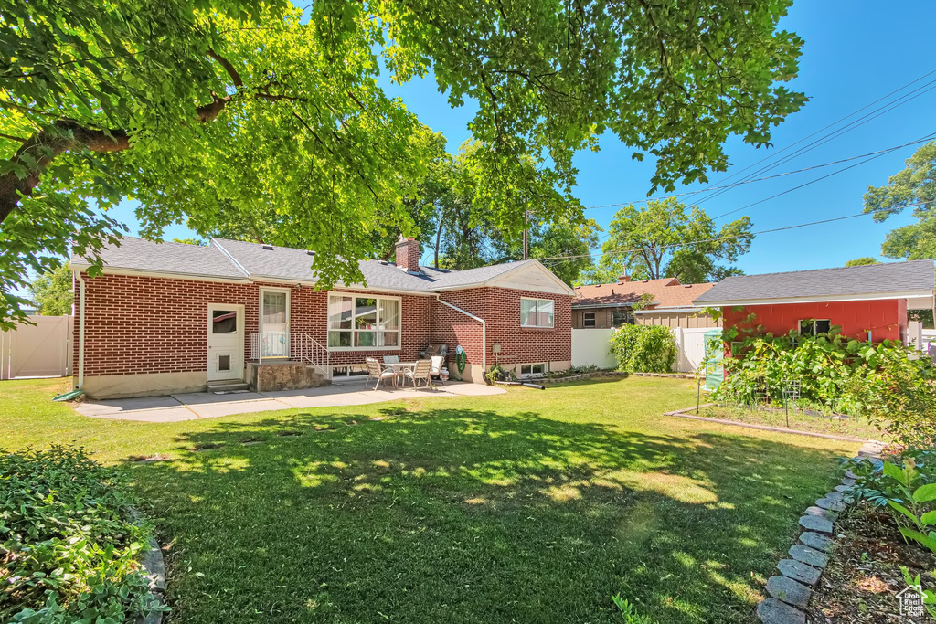 Rear view of house featuring a patio area, a chimney, a garden, entry steps, and brick siding