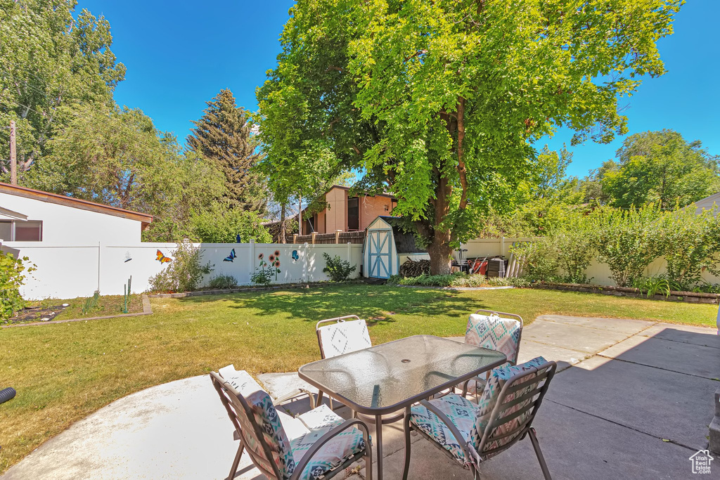 Fenced backyard with a storage unit, a patio, and outdoor dining area