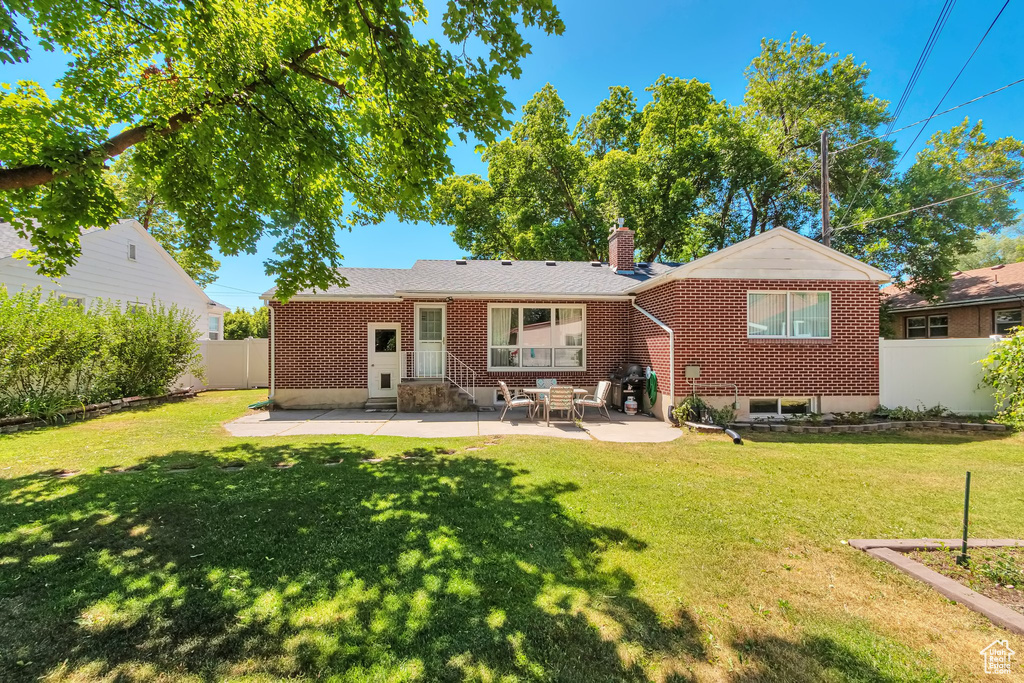 Back of house with a patio area, a chimney, and brick siding