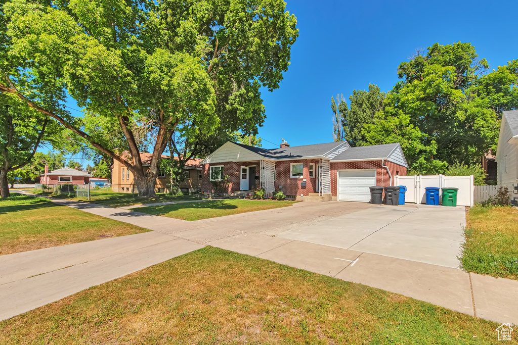 Ranch-style home with brick siding, an attached garage, driveway, and a chimney