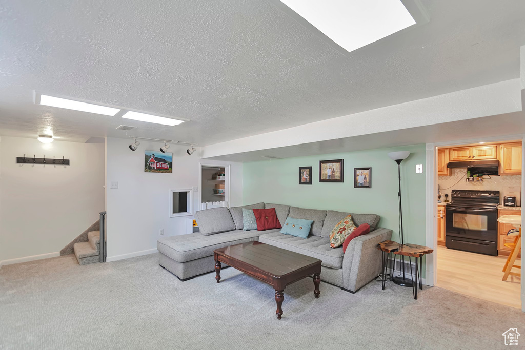 Living room with a textured ceiling, light carpet, and stairway