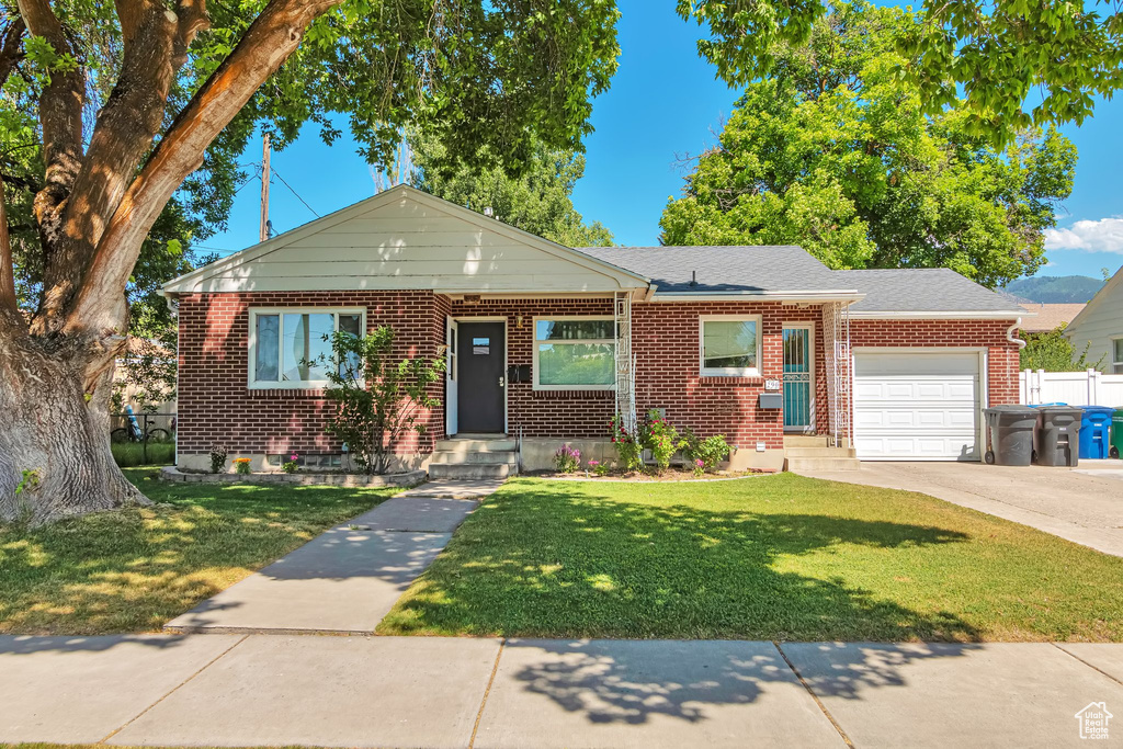 Bungalow-style home featuring an attached garage, brick siding, driveway, and roof with shingles