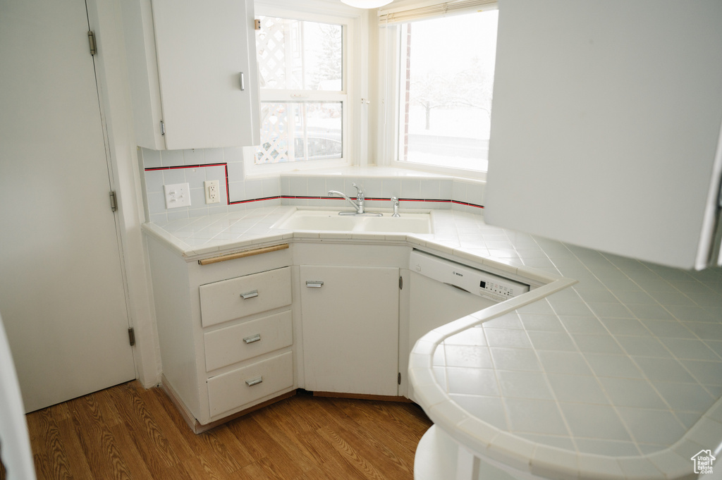 Kitchen featuring tile counters, white cabinets, and light wood-style floors