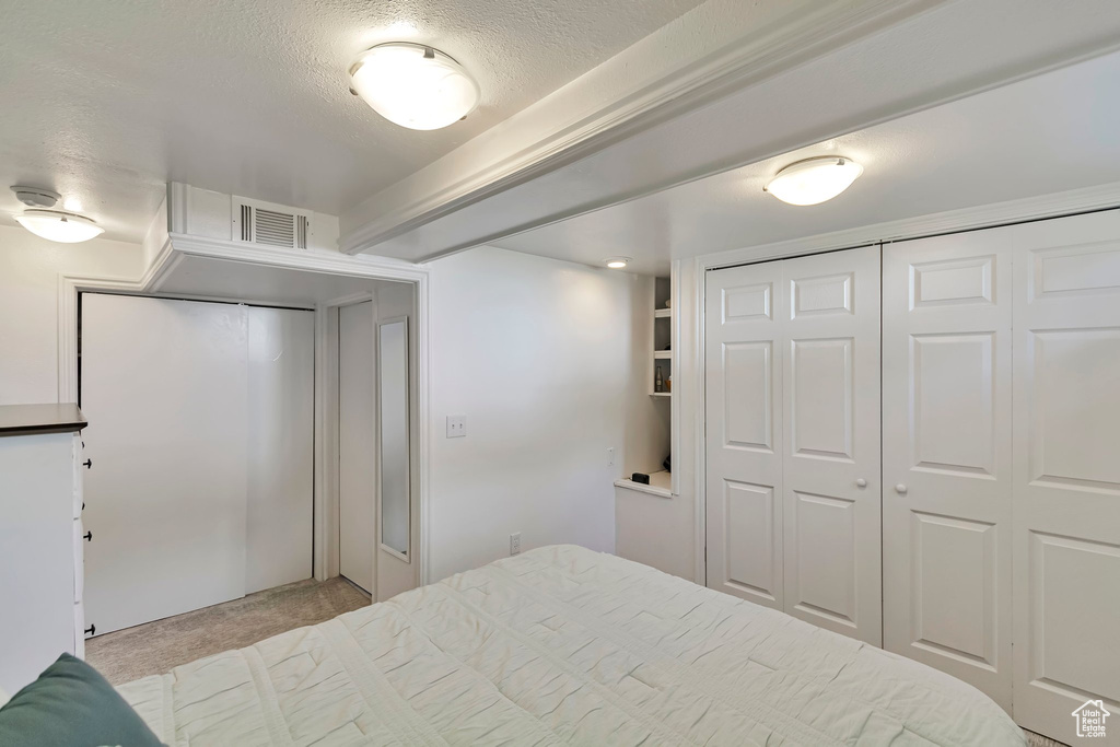 Carpeted bedroom with a textured ceiling and a closet