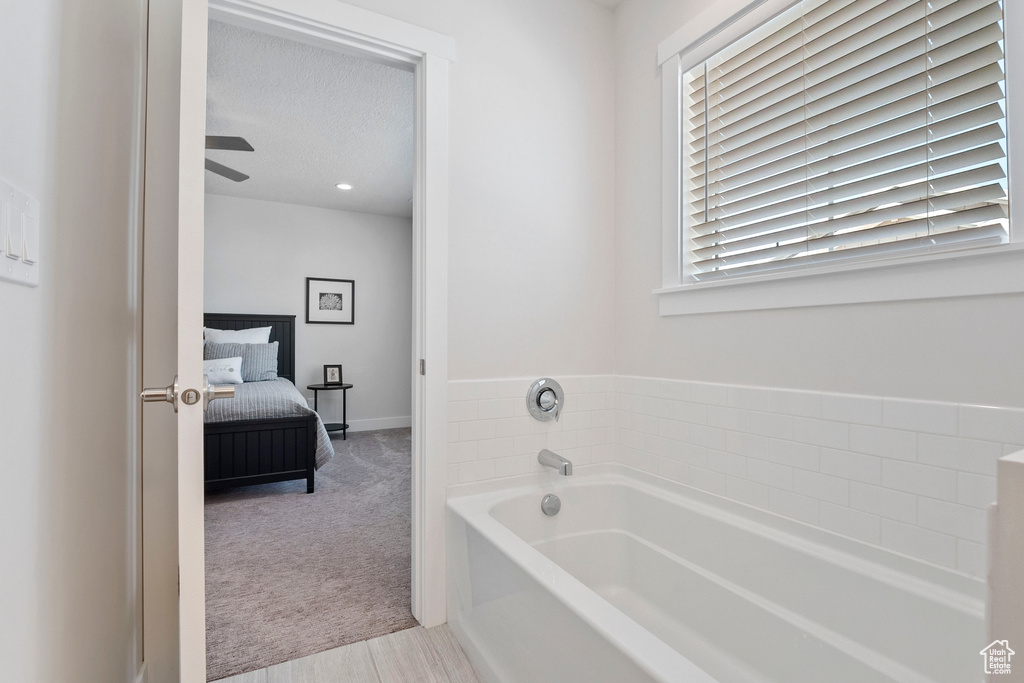 Bathroom with a bath, connected bathroom, plenty of natural light, and ceiling fan
