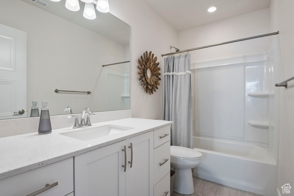 Bathroom featuring vanity, shower / tub combo, wood finished floors, and recessed lighting