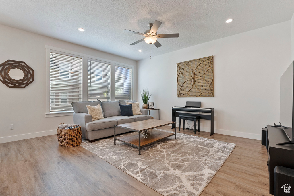 Living area with a ceiling fan, light wood-type flooring, recessed lighting, and a textured ceiling