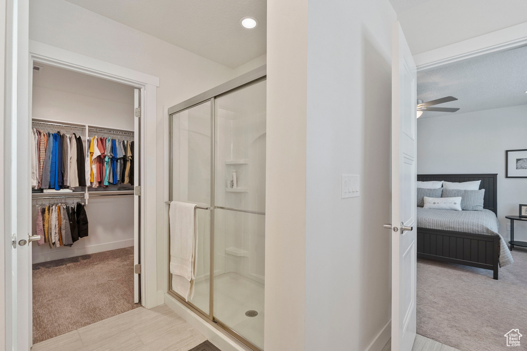 Full bath with a stall shower, a spacious closet, ceiling fan, and ensuite bath
