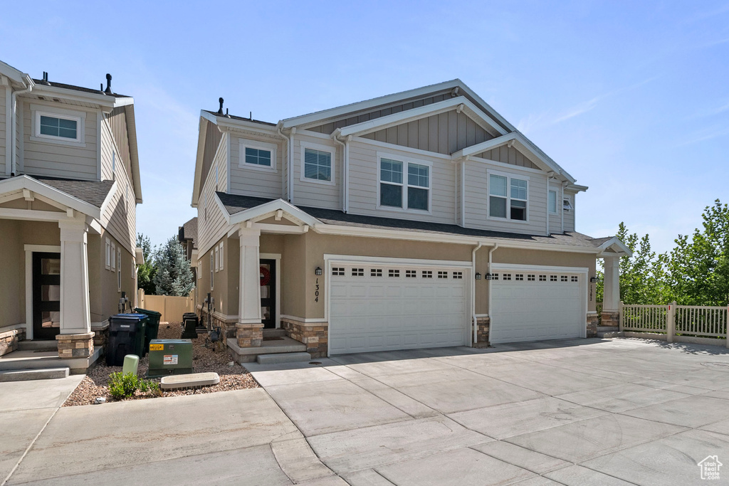 View of front of property featuring stone siding, board and batten siding, concrete driveway, and a garage