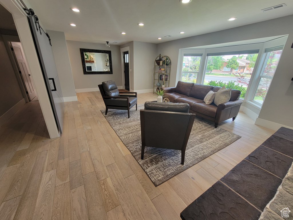 Living room featuring a barn door, recessed lighting, light wood-type flooring, and healthy amount of natural light