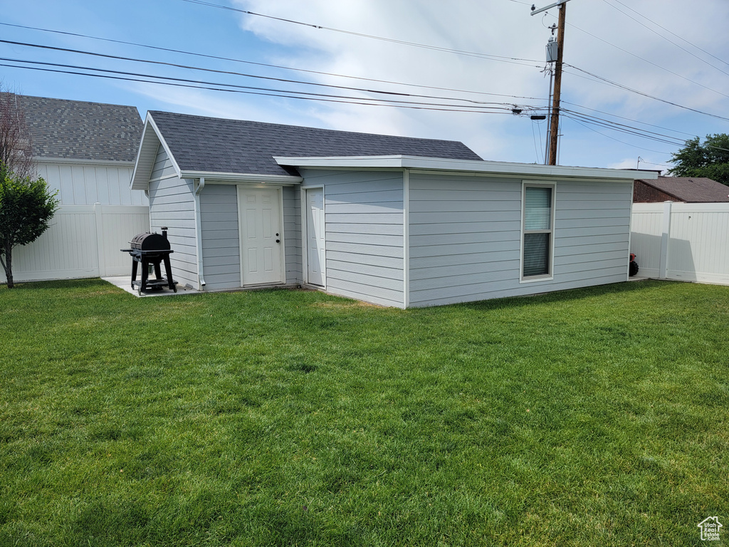 Back of house with a fenced backyard and a shingled roof