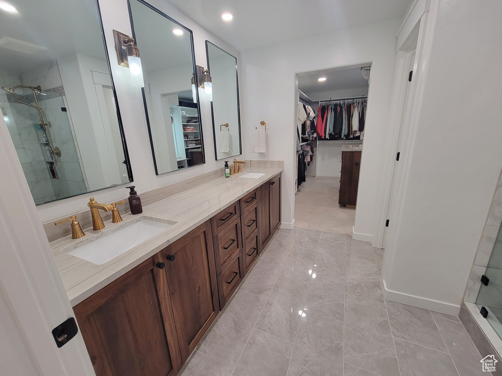 Bathroom with a walk in closet, a stall shower, double vanity, recessed lighting, and marble finish flooring