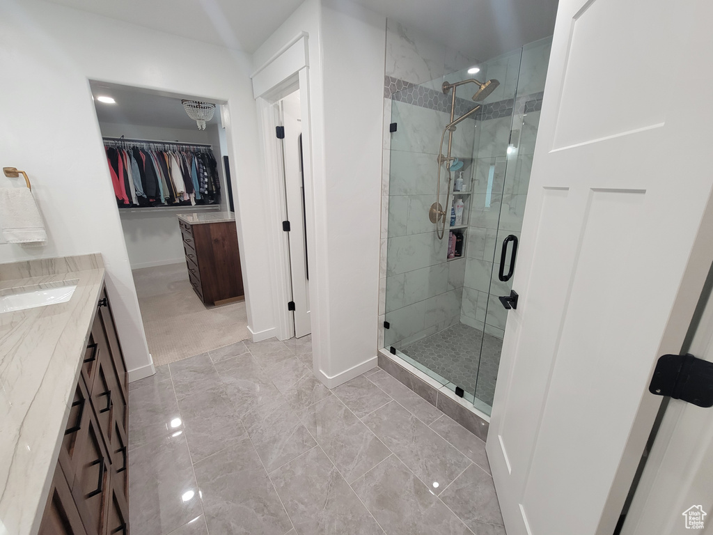 Bathroom with a shower stall, vanity, a walk in closet, and marble look tiles