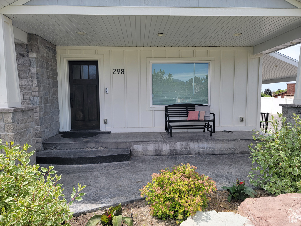 Entrance to property with board and batten siding, a porch, and stone siding