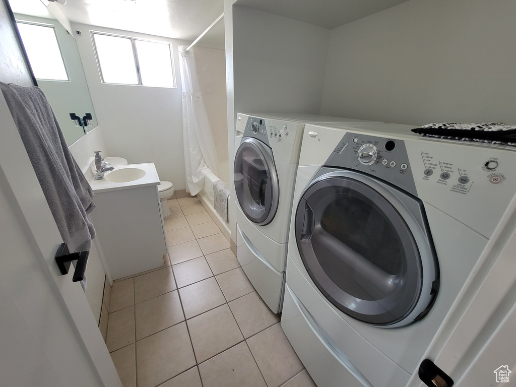 Washroom with separate washer and dryer and light tile patterned floors