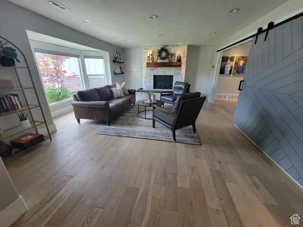 Living room with wood finished floors, a barn door, and a fireplace