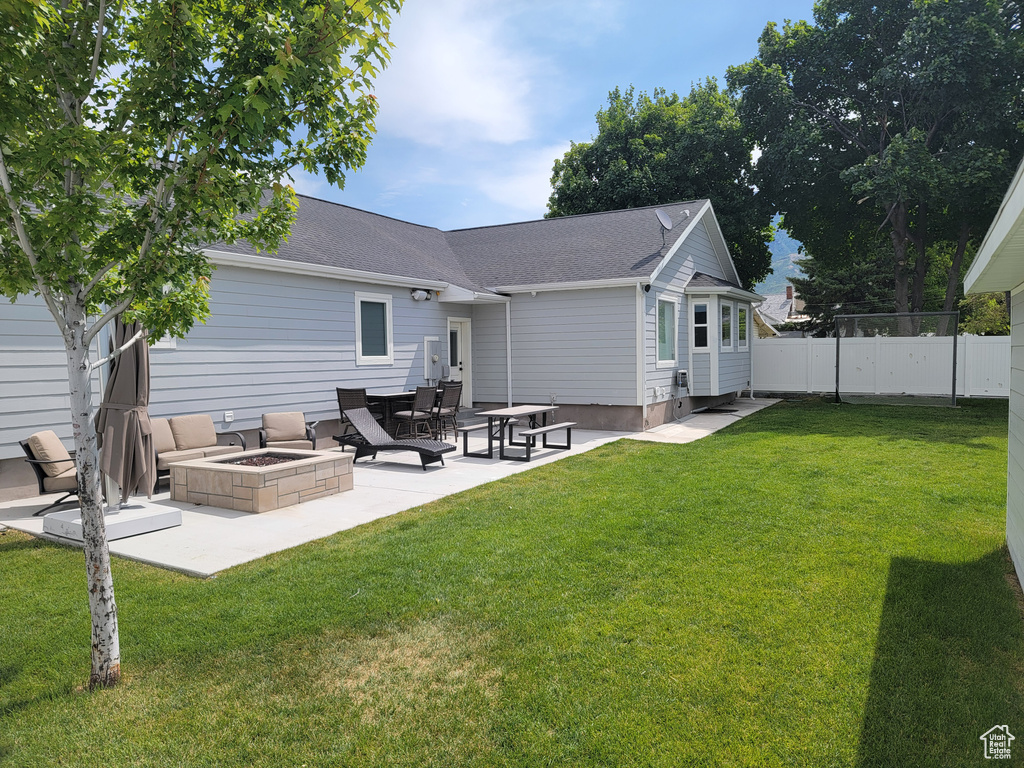 Rear view of property with a fire pit, a patio area, and a shingled roof