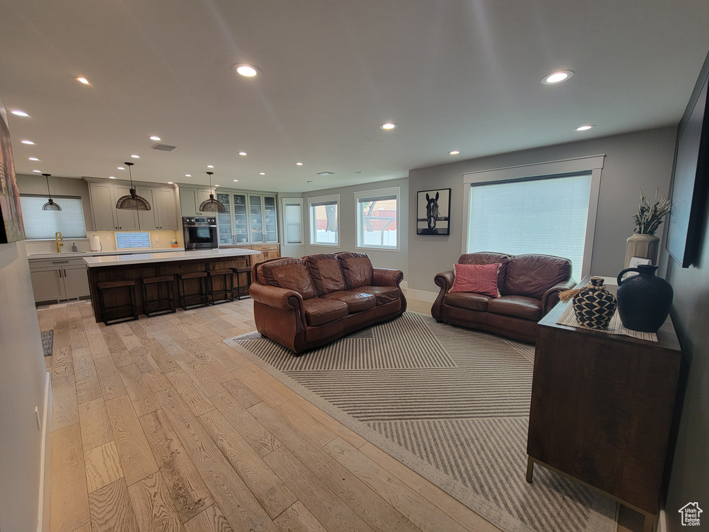 Living room with light wood-style flooring and recessed lighting