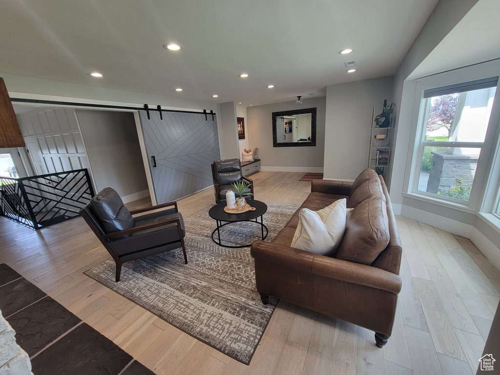 Living area with a barn door, recessed lighting, and wood finished floors