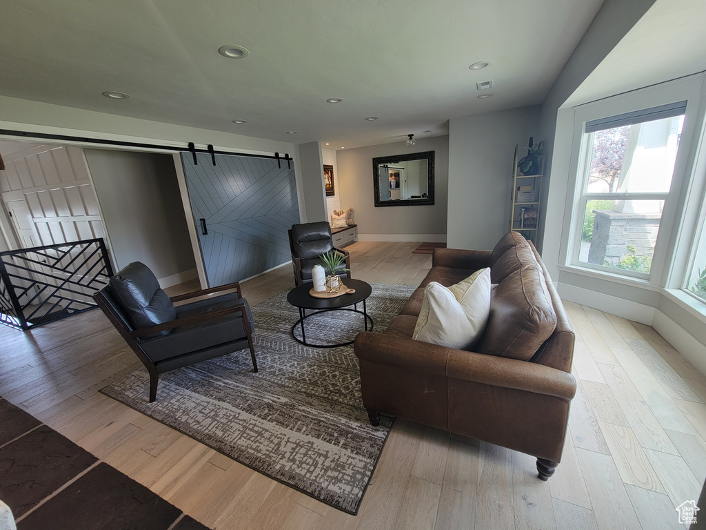 Living area with recessed lighting, a barn door, and wood finished floors