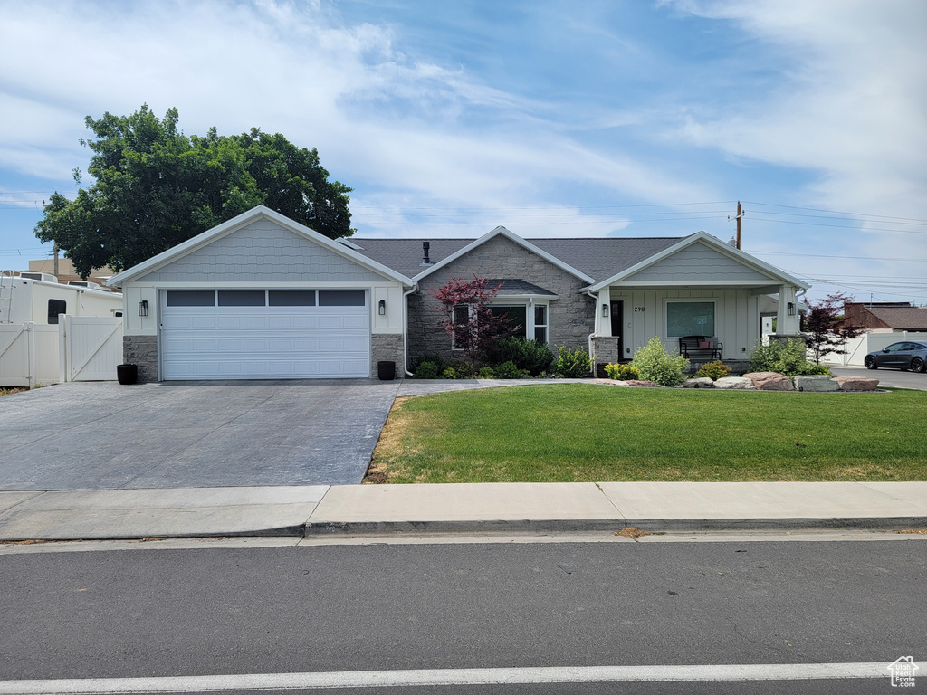 View of front of house featuring a gate, driveway, stone siding, and a garage