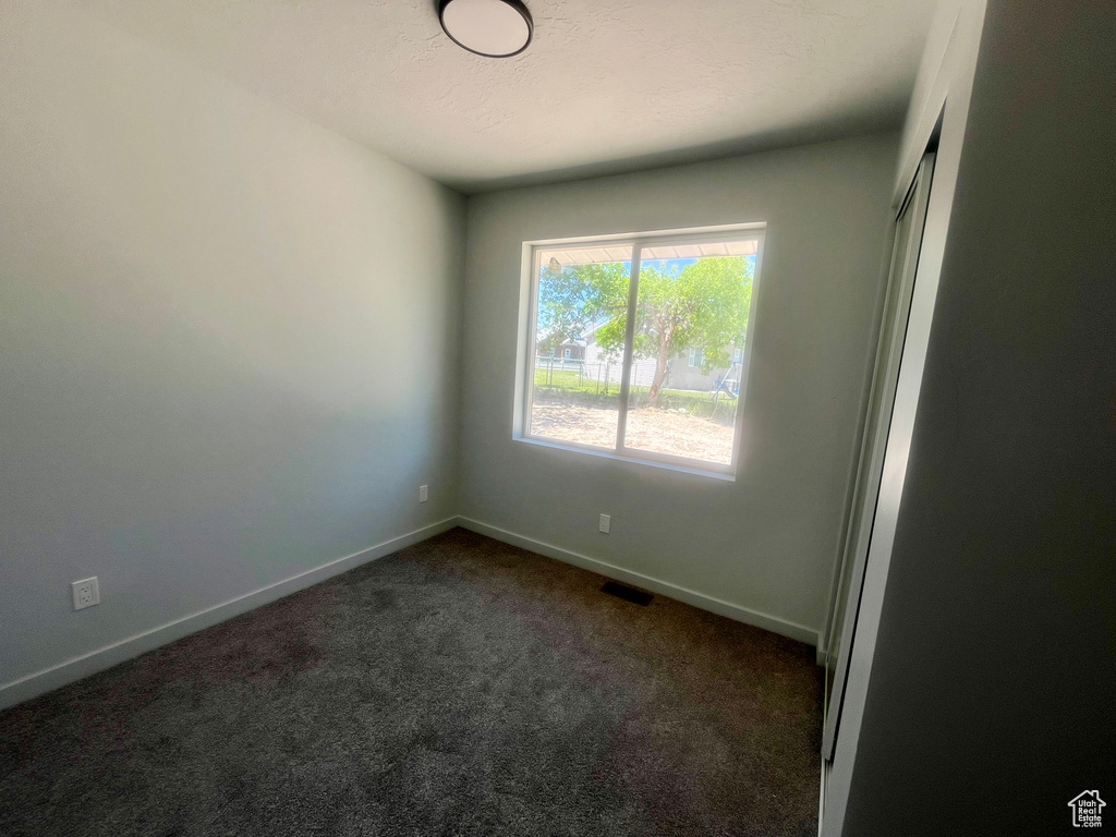 Empty room with dark carpet and baseboards