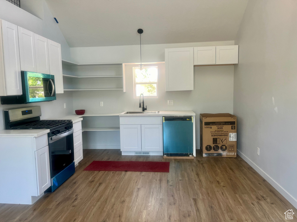 Kitchen featuring appliances with stainless steel finishes, lofted ceiling, white cabinetry, wood finished floors, and open shelves