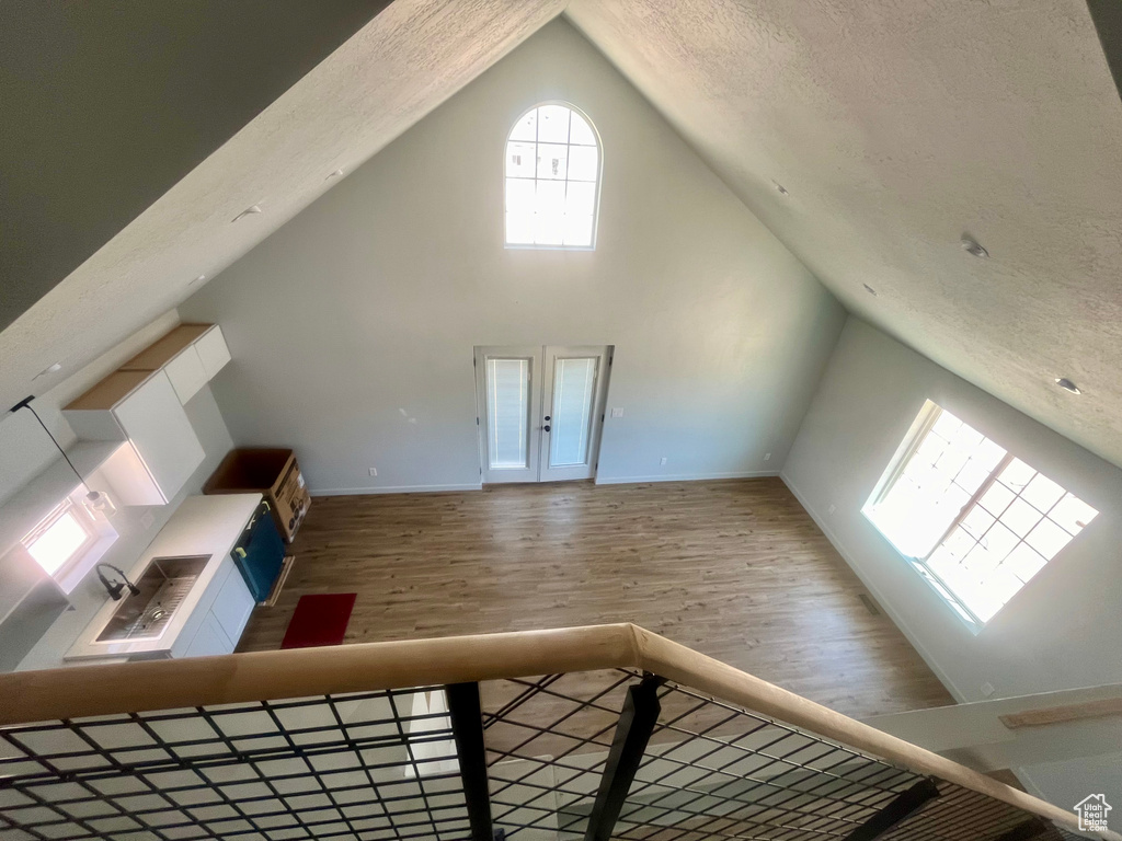 Bonus room featuring wood finished floors, a textured ceiling, and high vaulted ceiling