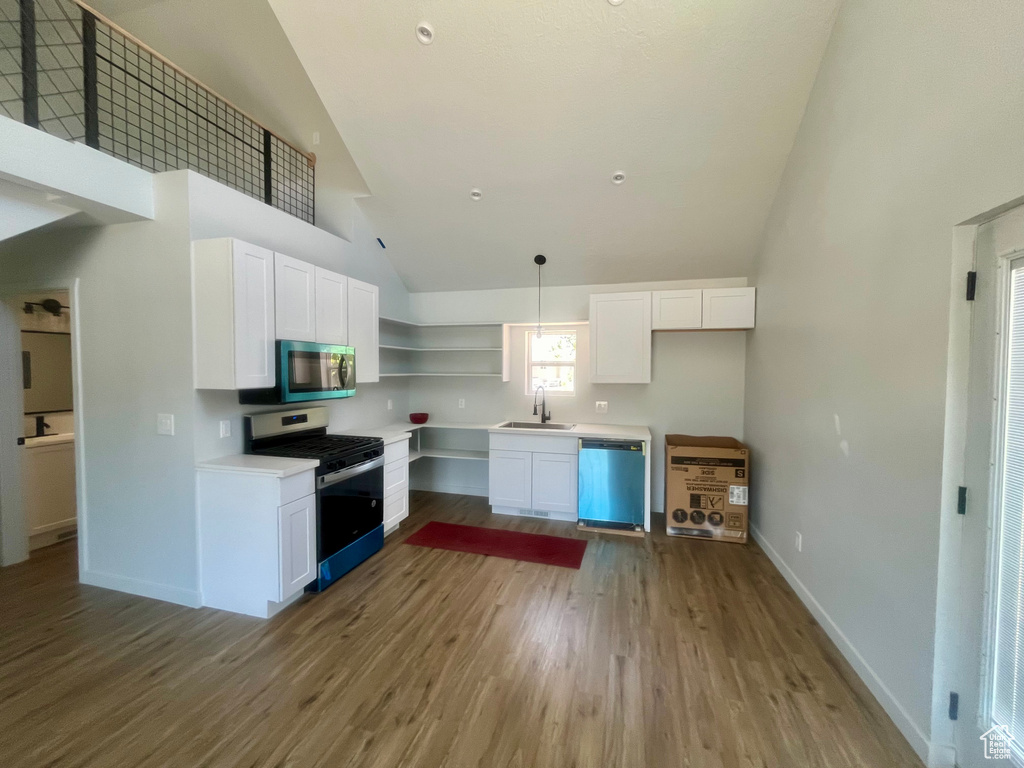 Kitchen with appliances with stainless steel finishes, high vaulted ceiling, light wood-style flooring, open shelves, and white cabinets