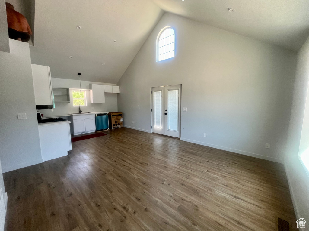Unfurnished living room featuring high vaulted ceiling, dark wood-style flooring, and french doors