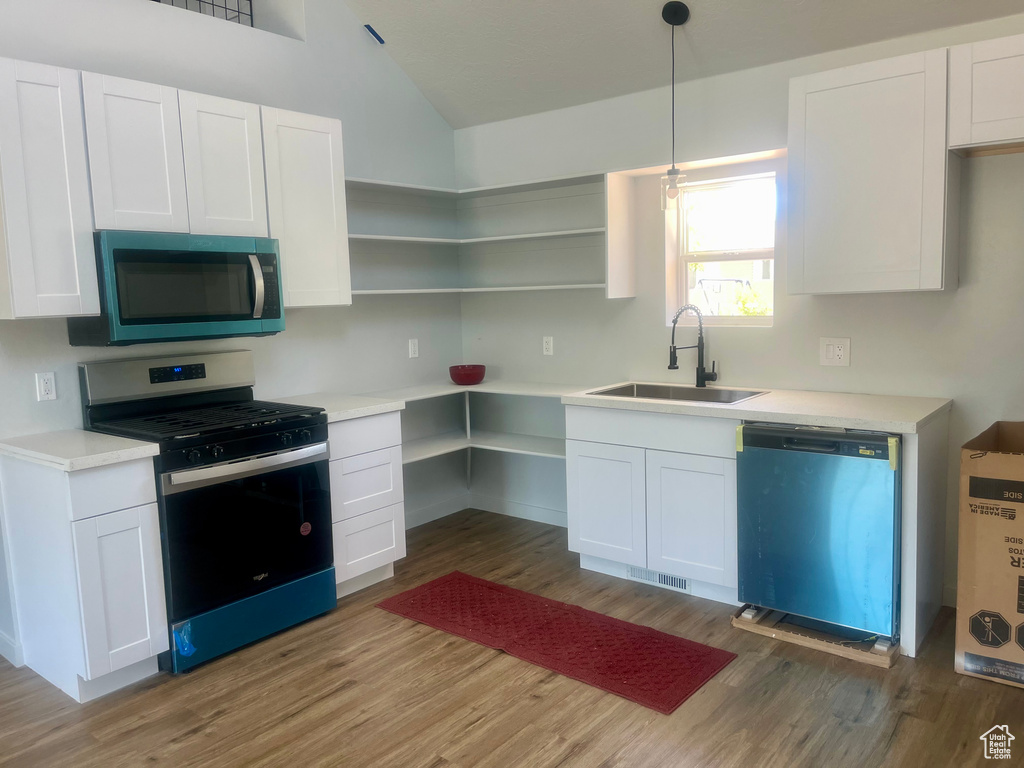 Kitchen with stainless steel gas range, dishwasher, wood finished floors, and lofted ceiling