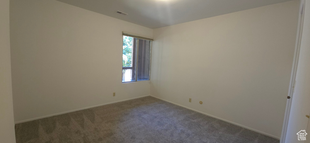 Empty room featuring dark carpet and baseboards