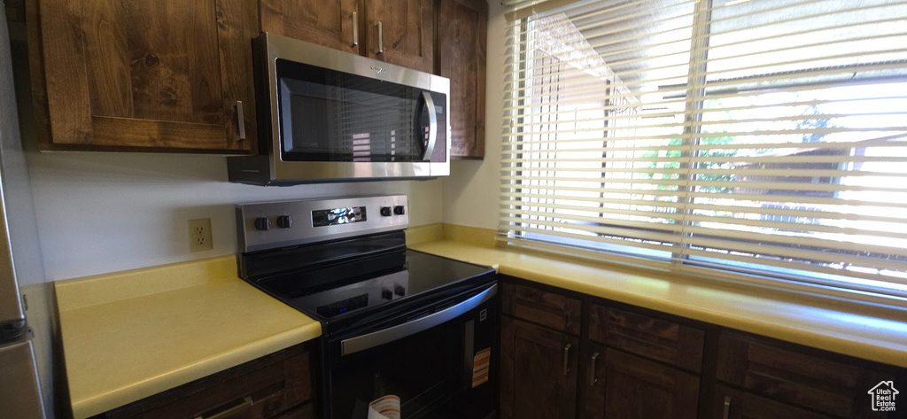 Kitchen with stainless steel appliances, light countertops, and dark brown cabinetry