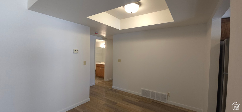 Corridor featuring light wood-style flooring and a tray ceiling
