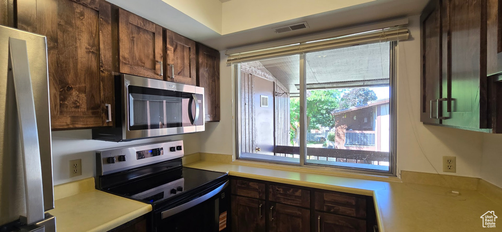 Kitchen featuring stainless steel appliances, light countertops, and dark brown cabinetry