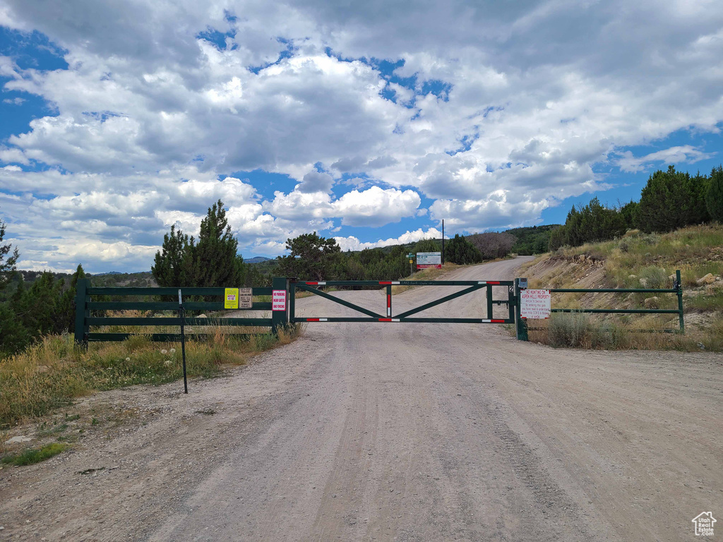 View of dirt / gravel road with a gate and a view of countryside