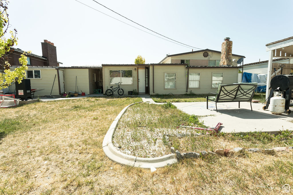 Back of house with a patio and a yard