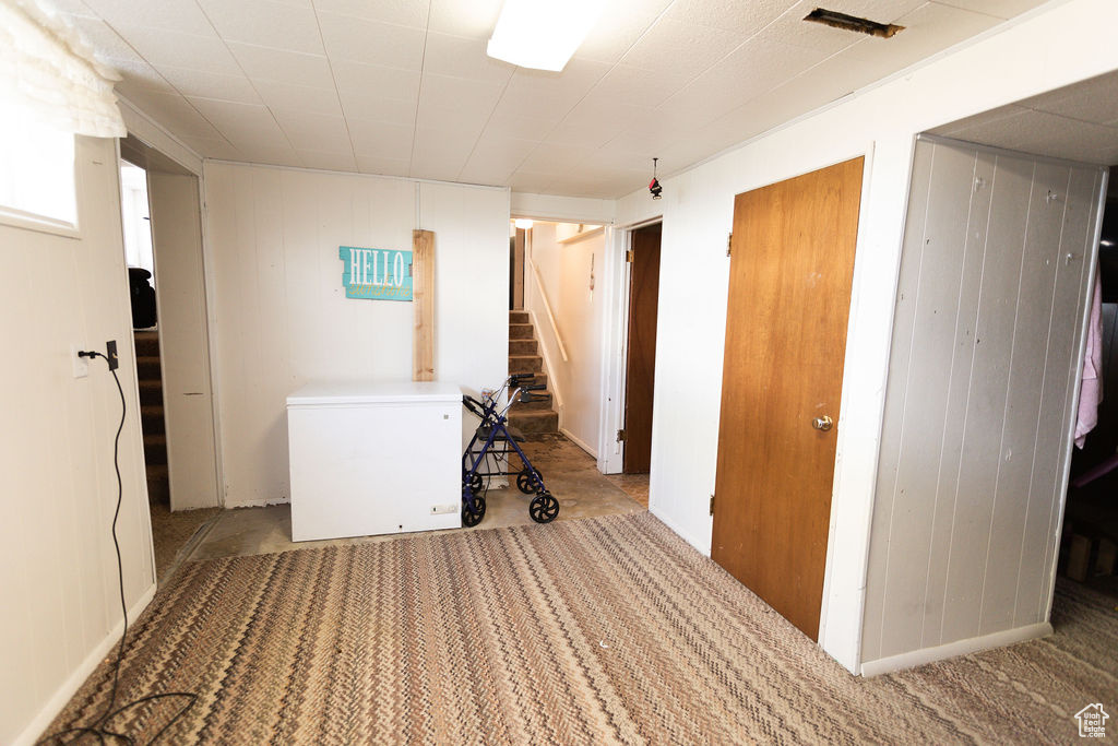 Carpeted spare room with stairway and wooden walls
