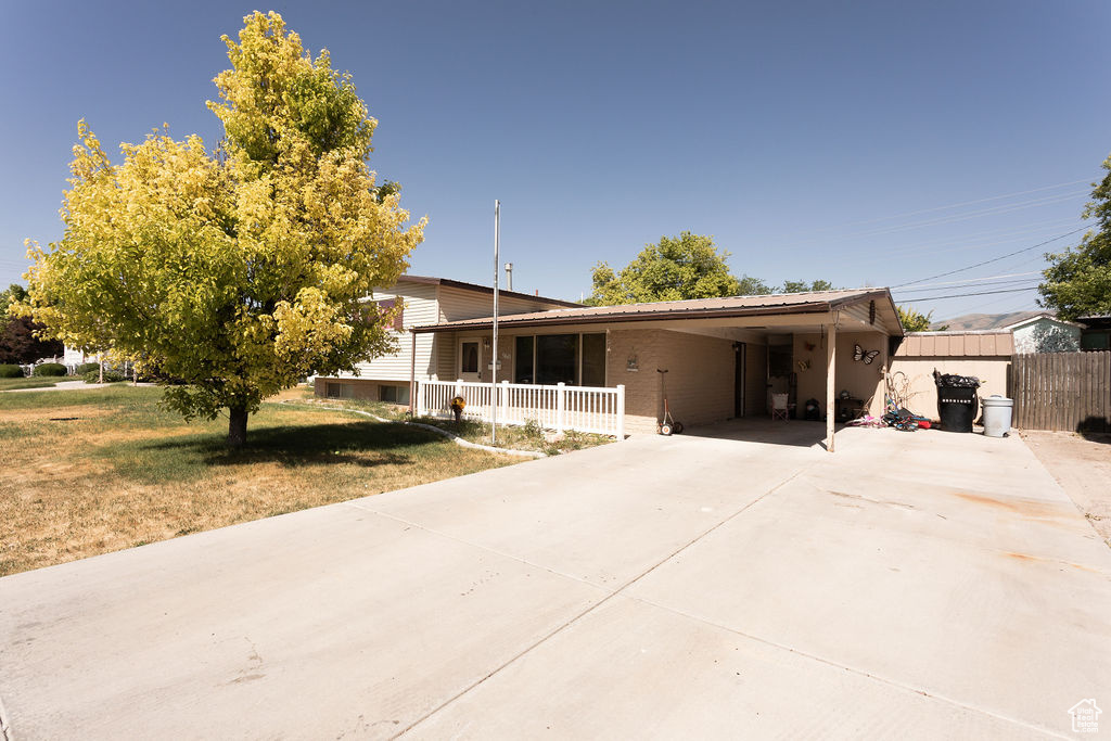 View of front of house featuring concrete driveway, a carport, and a porch