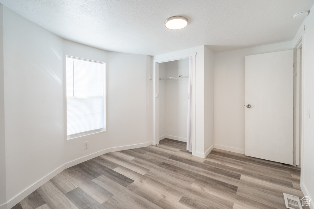 Unfurnished bedroom with light wood finished floors and a closet